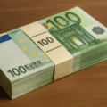 Pile de billets de 100 euros posée sur une table en bois